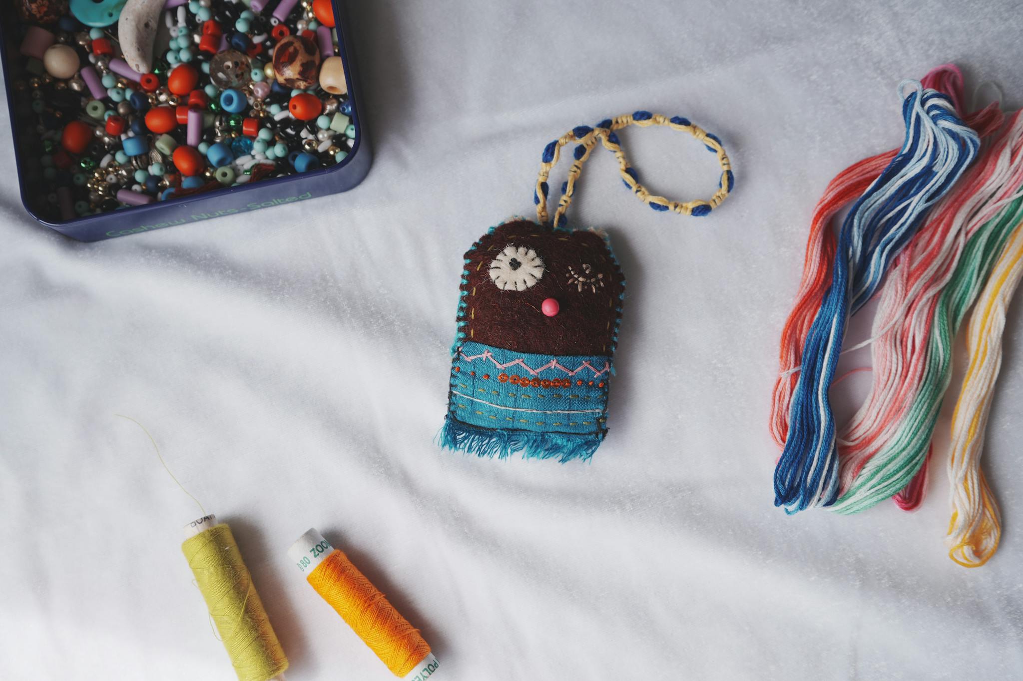Colorful collection of beads, threads, and a handcrafted item showcasing vibrant craft materials.